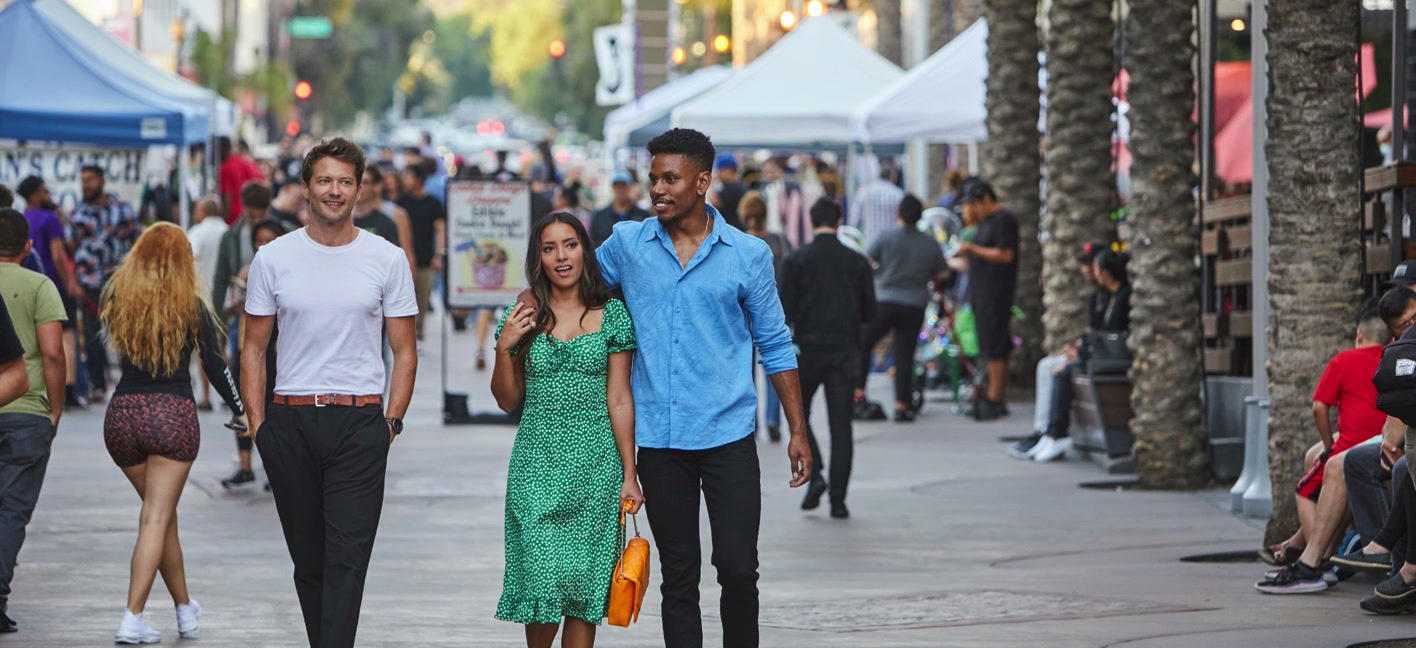 Friends stroll a tree-lined Burbank street on market day