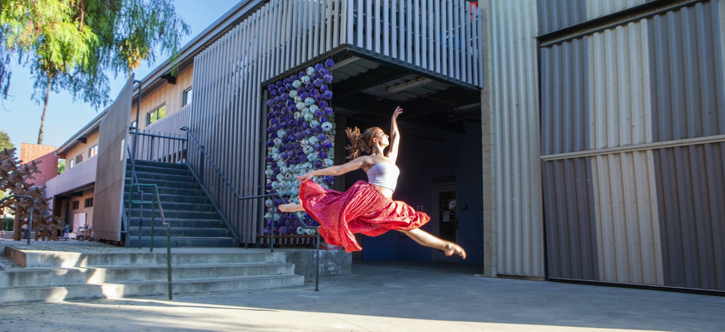 A dancer leaps in front of a downtown mural