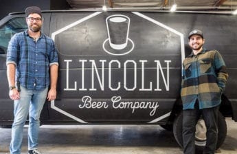 Lincoln Beer Company founders in front of their branded wall