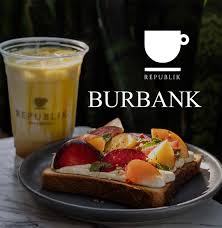 Republik coffee in a clear plastic cup with logo next to a plate of toast with colorful tomatoes on top