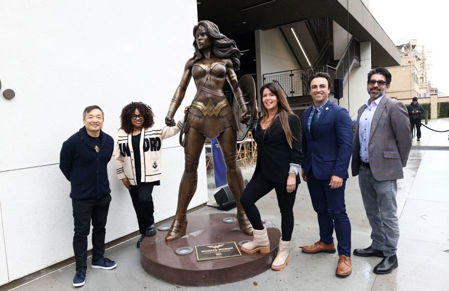 Five people stand around the wonder woman statue