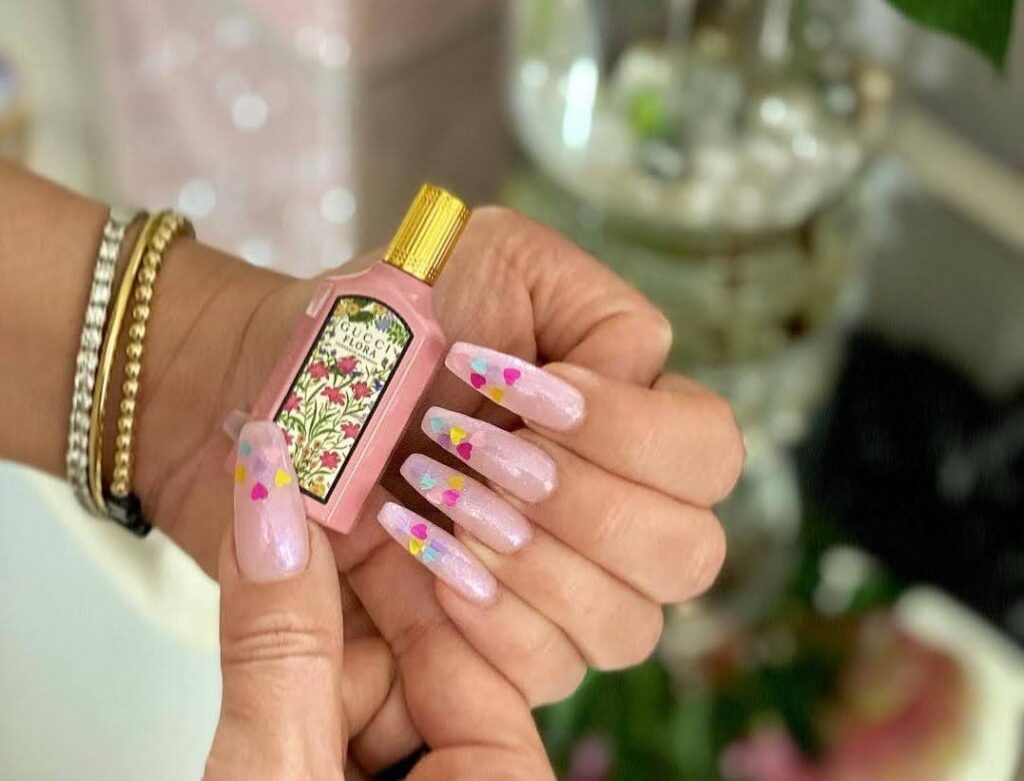 woman with pink nails holding a nail polish bottle