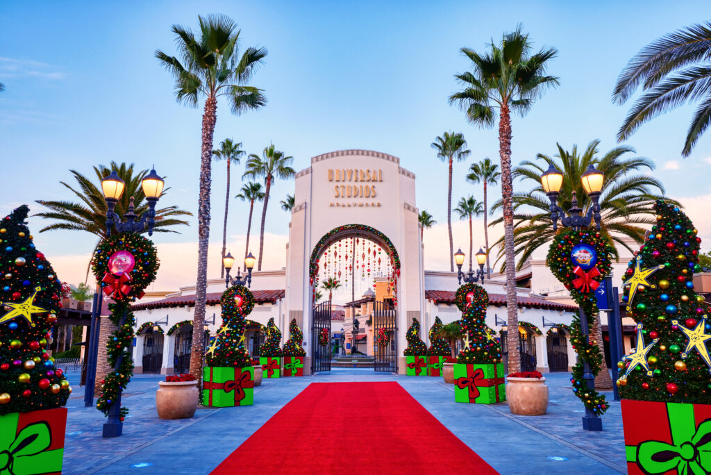 Universal Studios Hollywood front gate decorated for the holidays with red carpet, christmas lights, and giant red and green presents 