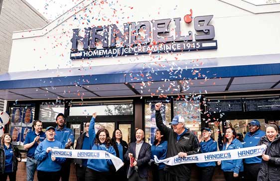 Staff celebrate in front of a Handels ice cream shop