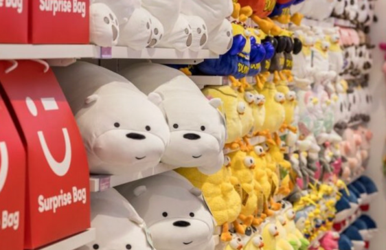 Shelves filled with plush toys and red surprise bags inside a Miniso store.