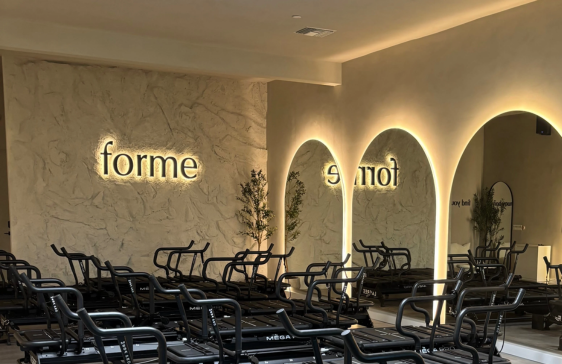 Interior of Forme fitness studio with Megaformer machines and illuminated arches.