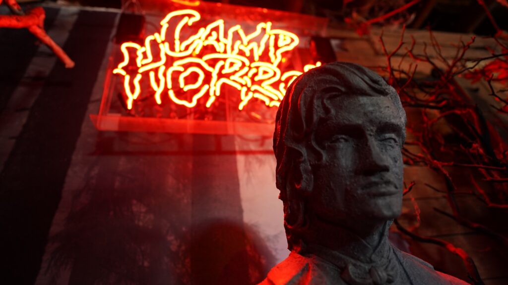 Red Camp Horror neon sign glowing above a stone bust at the Mystic Museum in Burbank