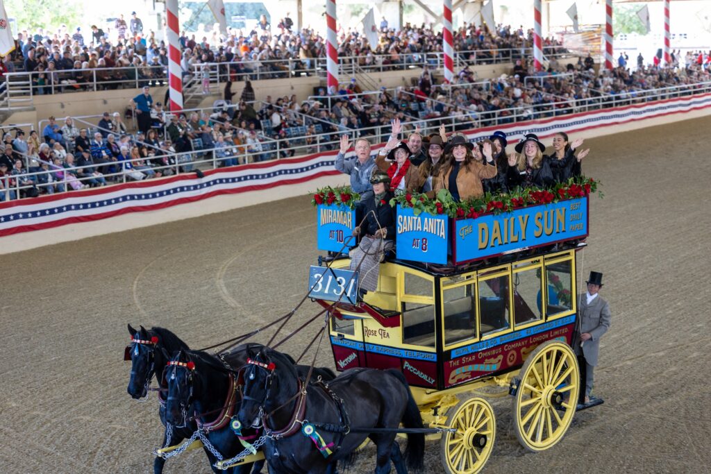 A horse-drawn stagecoach circles the arena in front of a full grandstand