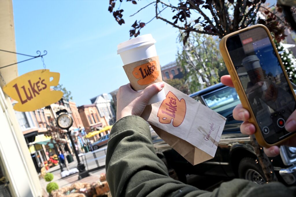 A visitor holds a Luke's Diner coffee cup up to the Luke's sign