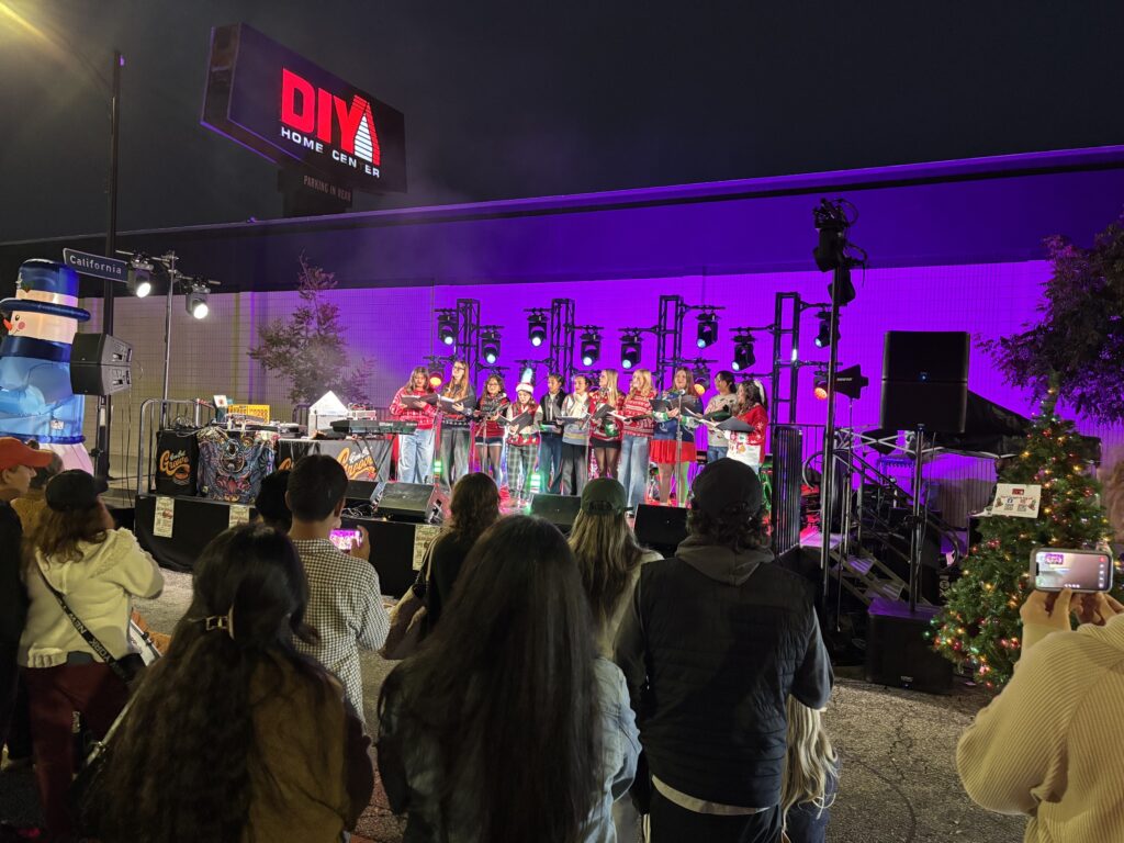 A choir performs on a purple-lit stage as a crowd watches