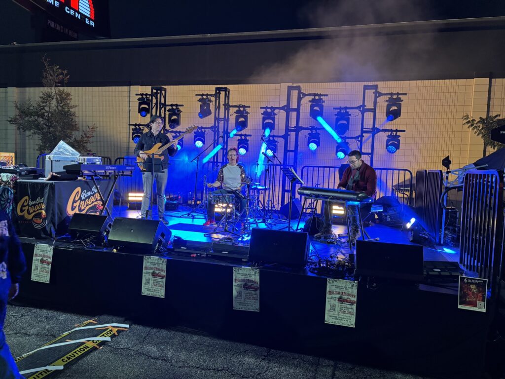 A band plays on a blue-lit outdoor stage