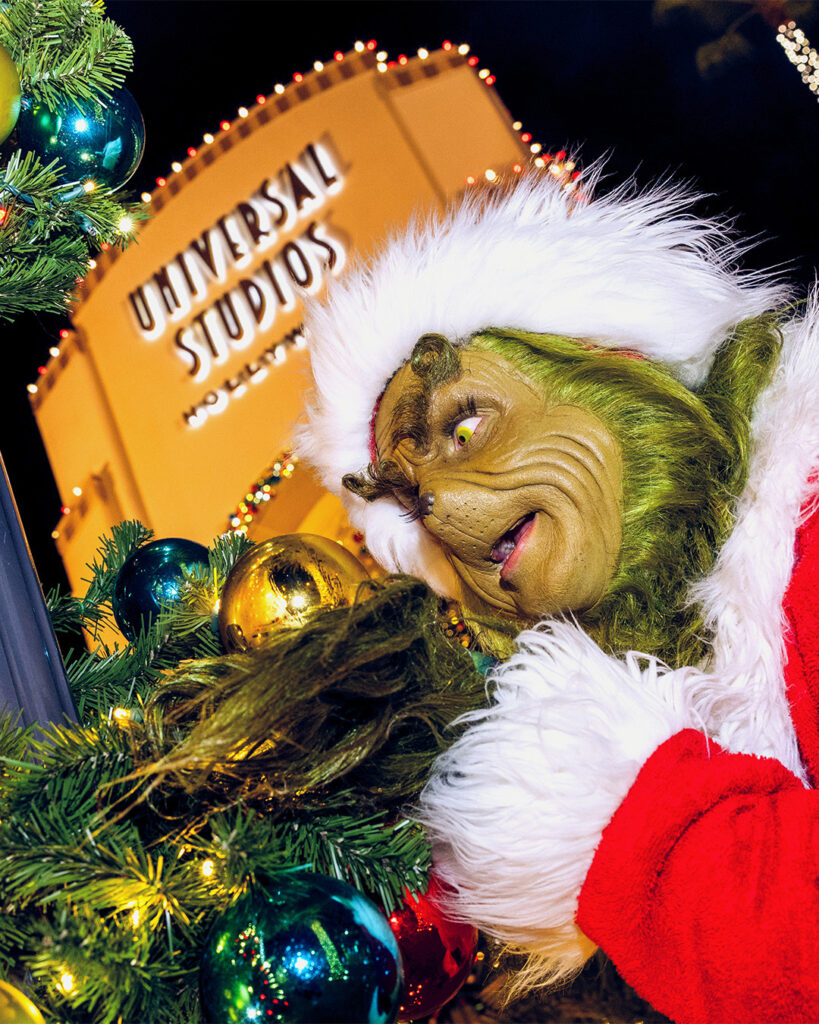 The Grinch in a Santa suit in front of the Universal Studios sign