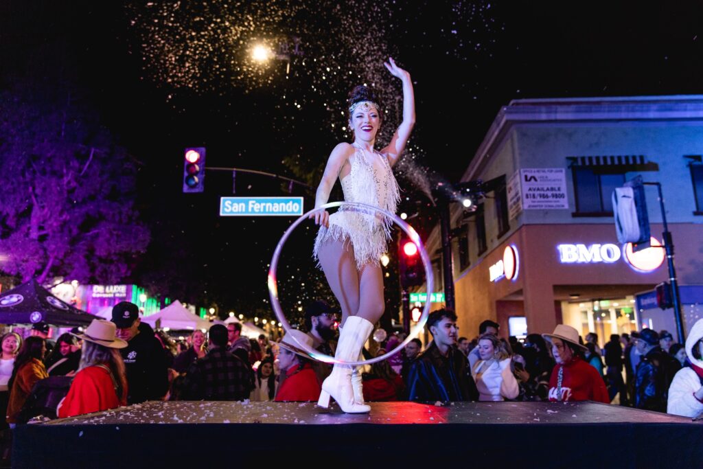 A hoop performer on stage under falling snow in Downtown Burbank