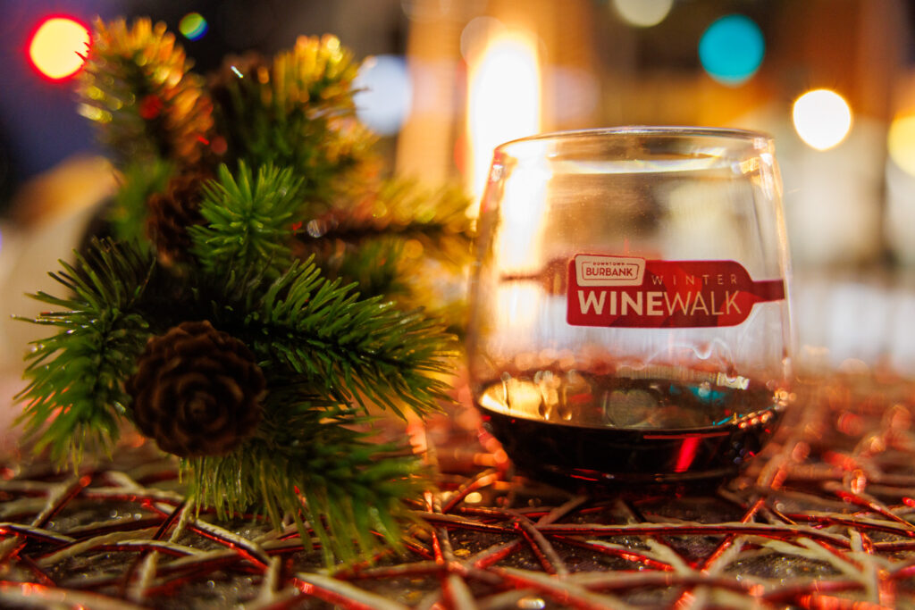 A Winter Wine Walk glass of red wine beside a pine sprig