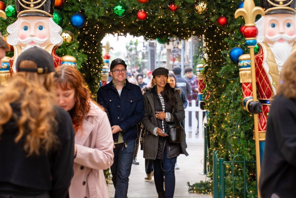 Visitors walk through a holiday arch flanked by giant nutcrackers