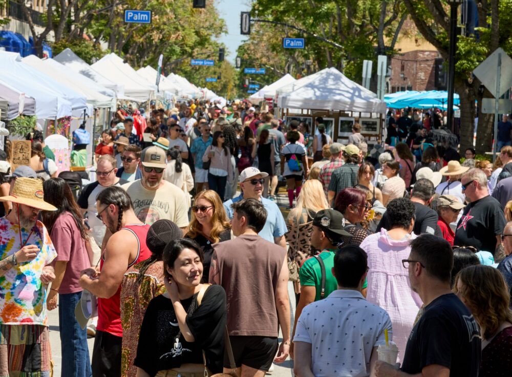 Crowds stroll past white artisan tents on San Fernando Boulevard