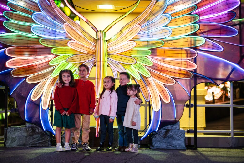 Children posing beneath a giant glowing butterfly lantern